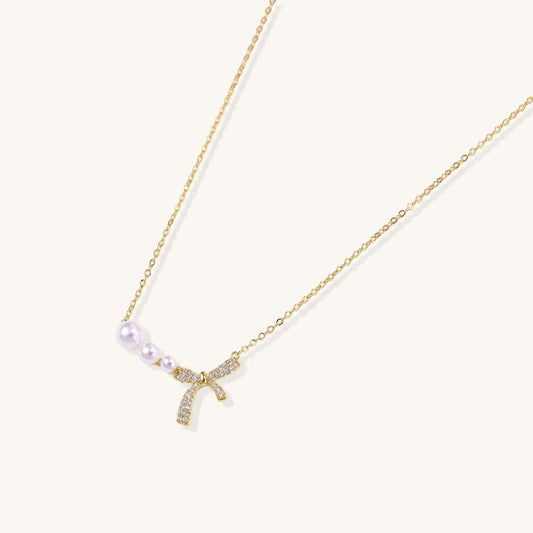 Pearl Bow Dreams Necklace featuring freshwater pearls and a crystal bow on a gold chain.