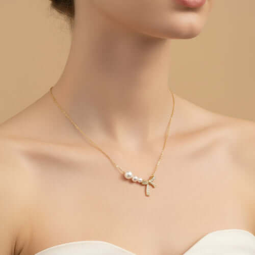 Woman wearing Pearl Bow Dreams Necklace featuring freshwater pearls and a sparkling crystal bow.