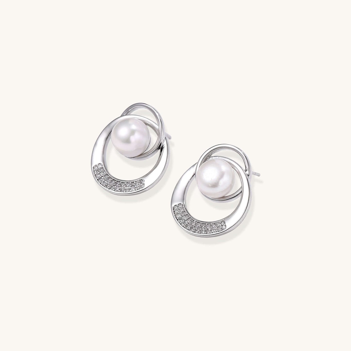 Gold-plated brass stud earrings with swirled circular design holding white freshwater pearls and small crystals