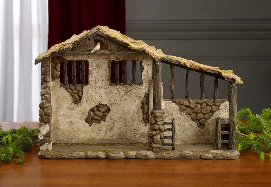 A lighted nativity stable model with a thatched roof, stone and stucco walls, and a manger in the center, designed for a 10 inch nativity set.