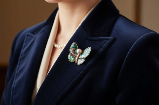 Rainbow Butterfly Brooch on navy blazer, showcasing iridescent abalone shell wings and freshwater pearl accents.