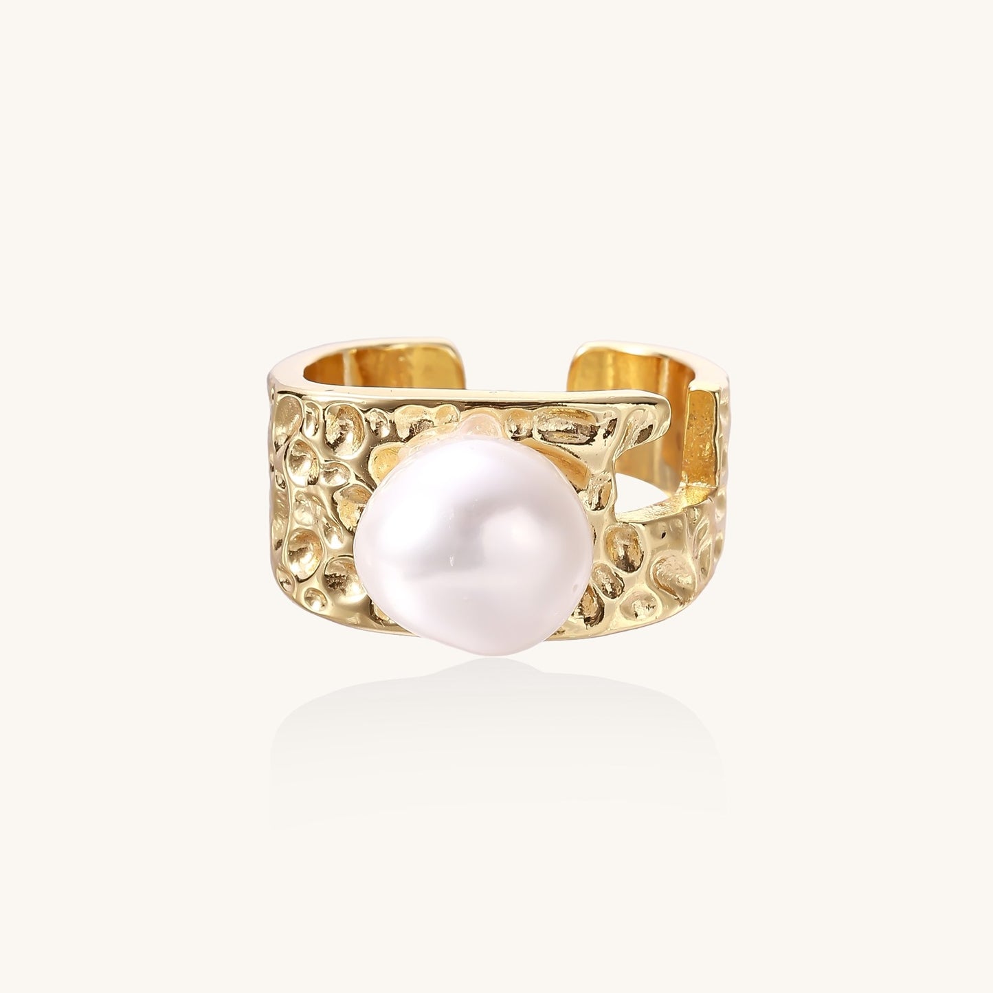Wide textured gold-plated brass ring with round freshwater pearl centerpiece on neutral background
