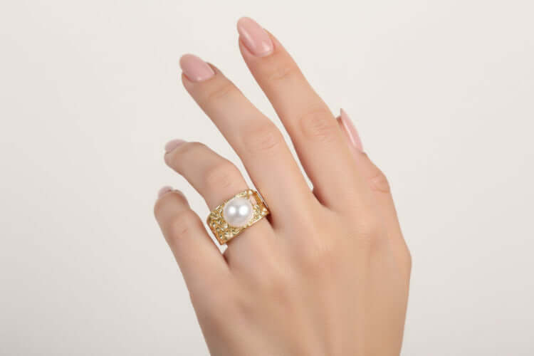 Golden Tide Pearl Ring on a woman's hand showcasing the hammered gold design and lustrous freshwater pearl.