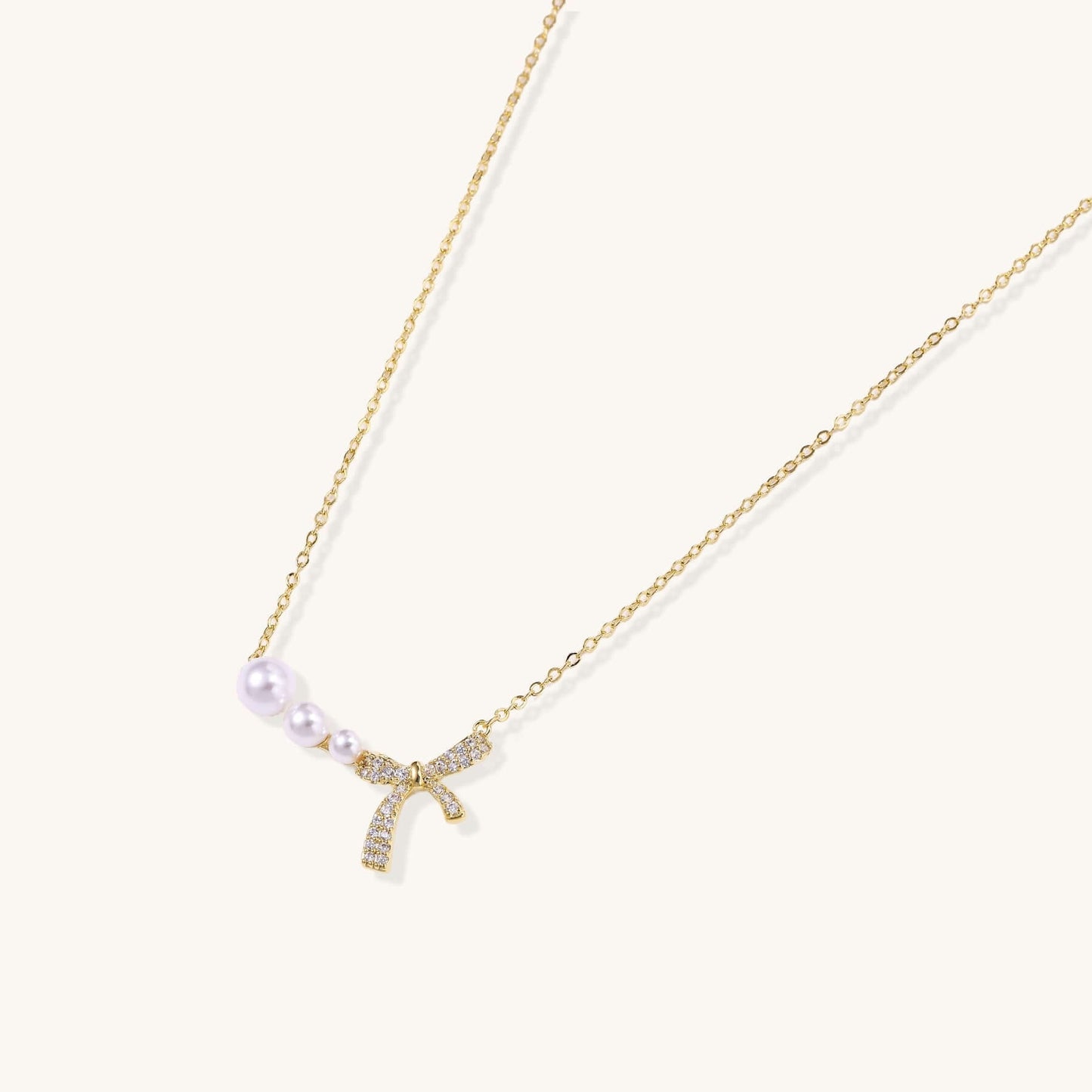 Pearl Bow Dreams Necklace featuring freshwater pearls and a crystal bow on a gold chain.