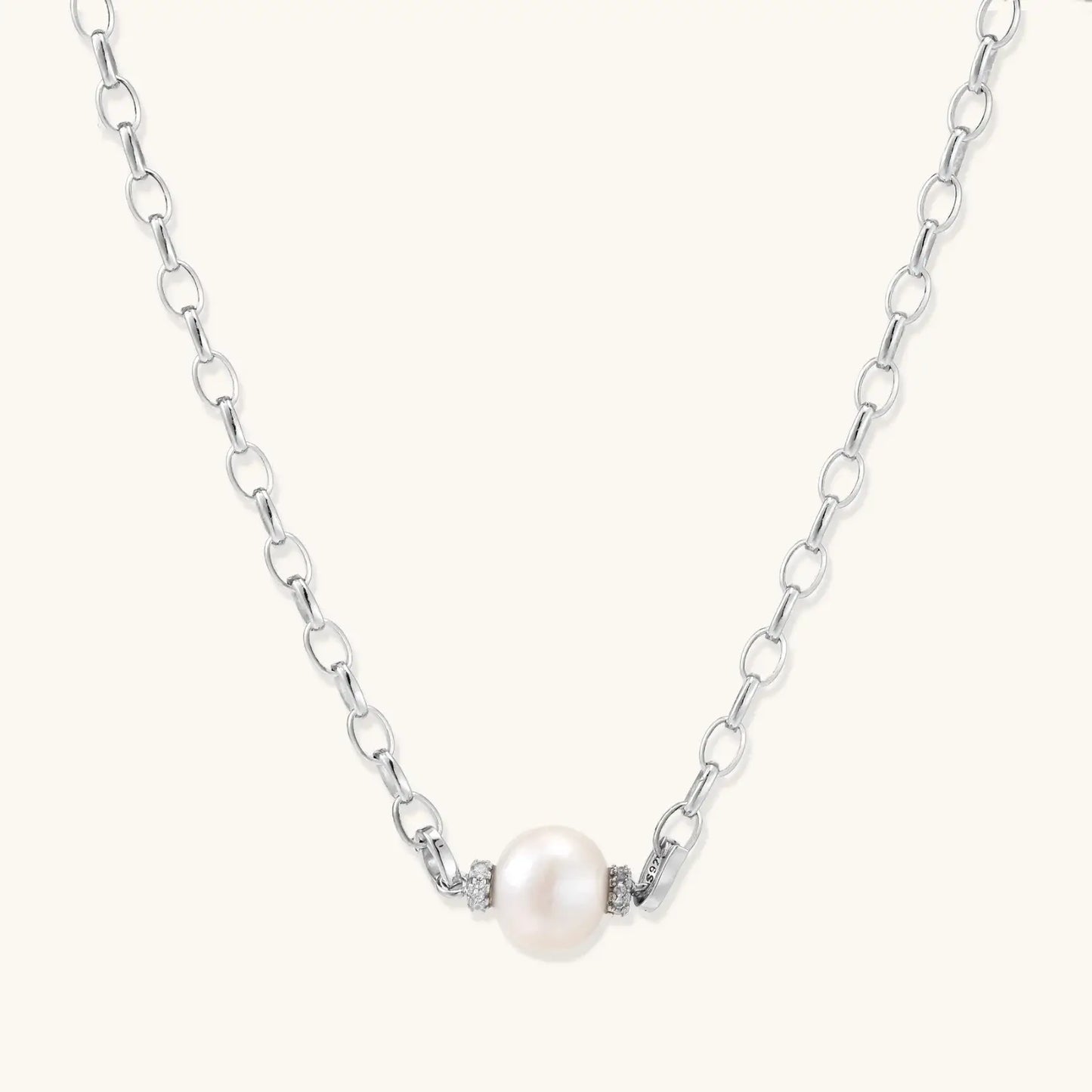 Dainty rhodium-plated silver chain necklace with centered 10mm freshwater pearl and crystal accents on cream background