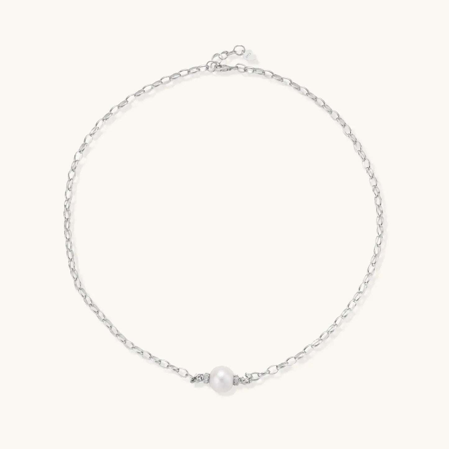 Dainty rhodium-plated silver chain necklace with centered 10mm freshwater pearl and crystal accents on cream background