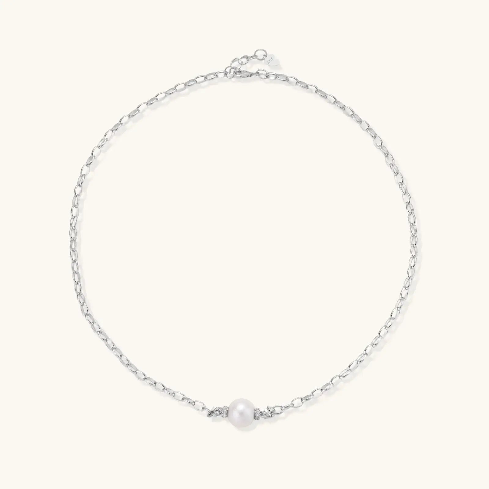 Dainty rhodium-plated silver chain necklace with centered 10mm freshwater pearl and crystal accents on cream background