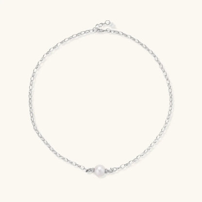 Dainty rhodium-plated silver chain necklace with centered 10mm freshwater pearl and crystal accents on cream background