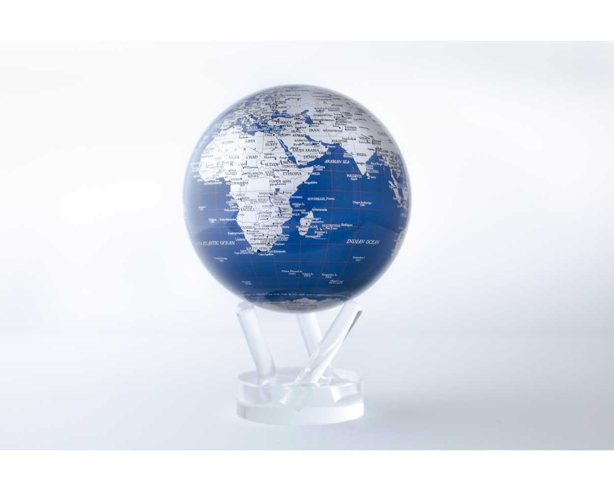 A rotating globe with silver landmasses on a blue background, set on a clear stand, demonstrating ambient light-powered technology.