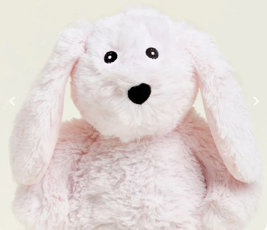 A pink plush bunny-shaped warmie with a face printed on its side, designed for microwave and freezer use.
