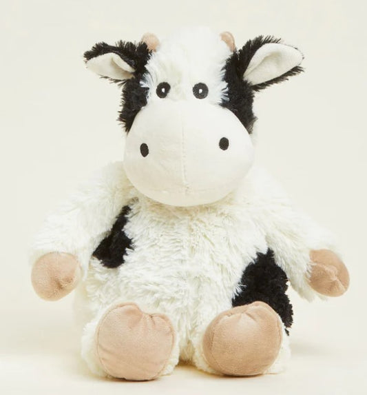 A plush toy resembling a black and white cow with a soft texture, designed to be microwavable and scented with lavender.
