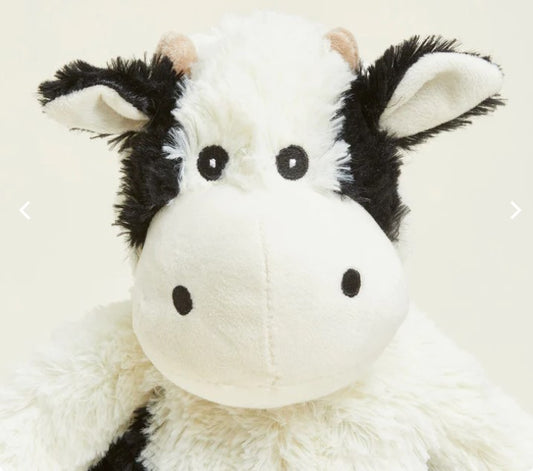 A plush toy resembling a black and white cow with a soft texture, designed to be microwavable and scented with lavender.