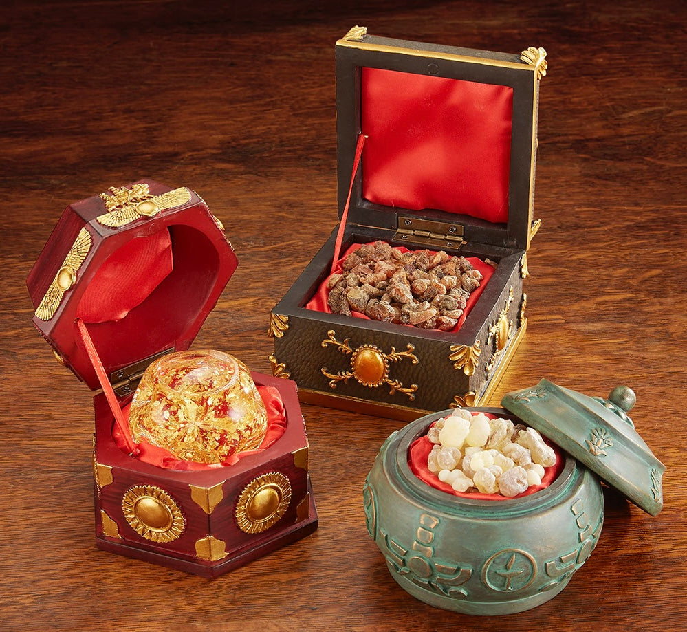 Three decorative faux wooden boxes with lids, containing gold flakes in a glass ball, frankincense, and myrrh, each box is satin-lined.