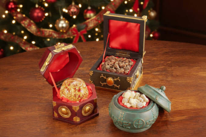 Three decorative boxes with gold, frankincense and myrrh.  Red, and green colors on a wooden surface.