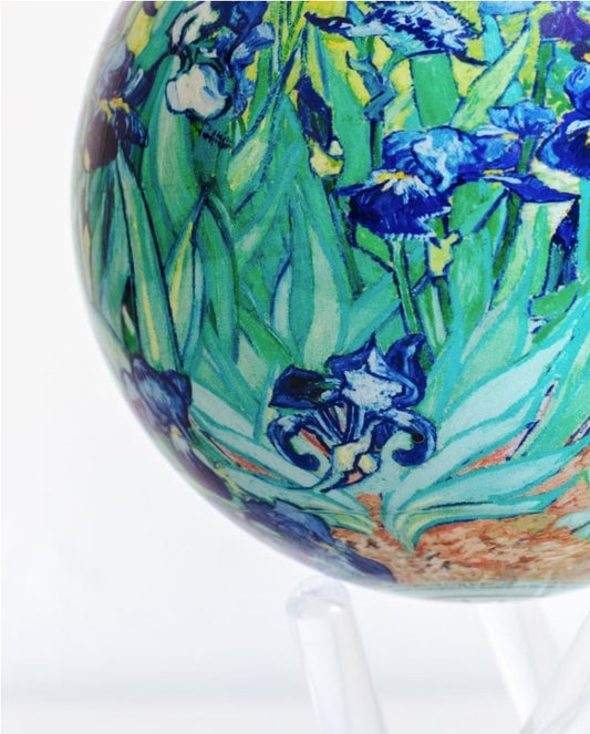 A rotating globe featuring the 'Irises' painting by Van Gogh with a field of purple and white flowers and a golden field in the background, set on a clear stand.