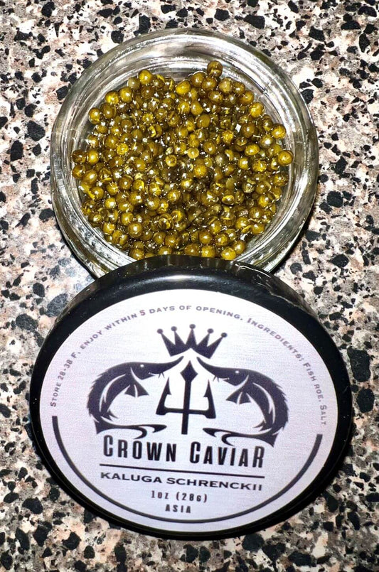 A tin can of Crown Caviar Kaluga Schrenckii with a label showing the brand name, the type of caviar, and the weight of 1 oz (28g). The background appears to be a textured surface, possibly a countertop.
