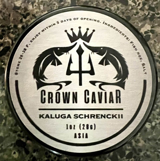 A tin can of Crown Caviar Kaluga Schrenckii with a label showing the brand name, the type of caviar, and the weight of 1 oz (28g). The background appears to be a textured surface, possibly a countertop.