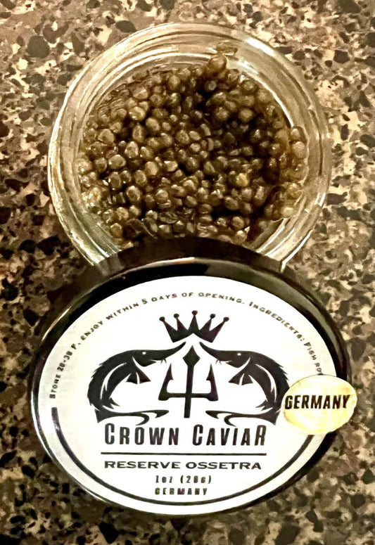 A tin can labeled 'Crown Caviar Reserve Ossetra' with a weight indication of 1 oz (28g) and the text 'Germany'. The can is designed with a black and white color scheme featuring fish graphics, and there is a badge indicating 'Gourmet Selection'.