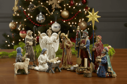 Nativity scene with figurines in front of a decorated Christmas tree.