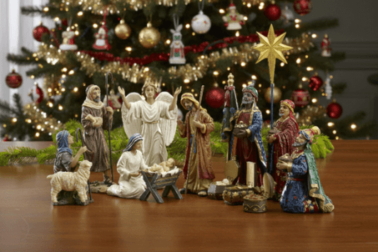 Nativity scene with figures in front of a decorated Christmas tree.