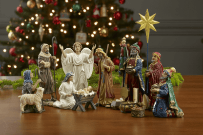Nativity scene figurines with a Christmas tree in the background