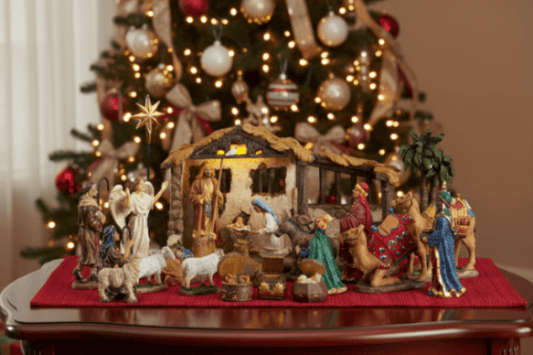 Nativity scene with three wise men and a star in front of a decorated Christmas tree.