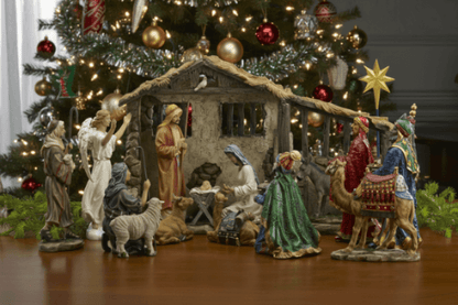Nativity scene with figures in front of a decorated Christmas tree.