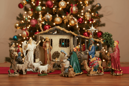 Nativity scene with figures in front of a decorated Christmas tree.