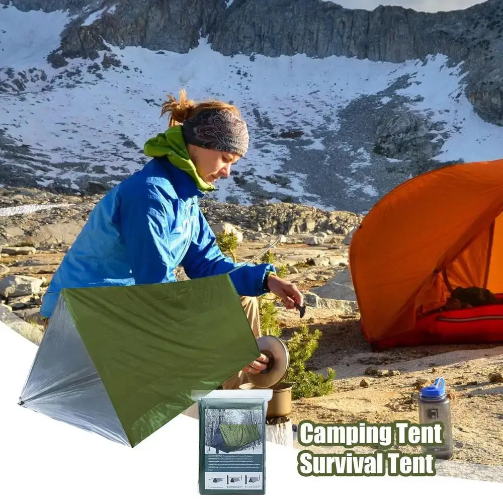 Outdoor Emergency Survival Tent and Blanket in use at a campsite with a person setting it up in the wilderness.