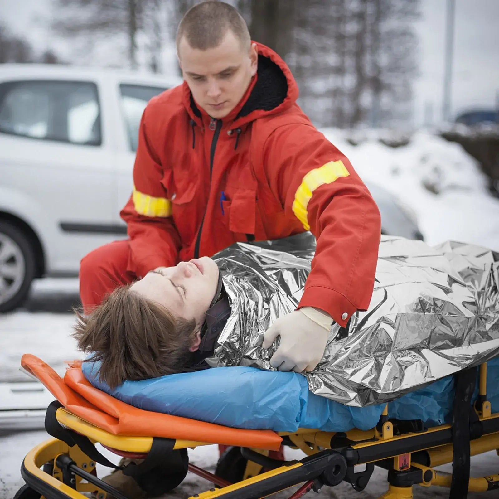 Emergency Solar Blanket for Hunting or Camping being used by a rescuer on a patient in snowy conditions.