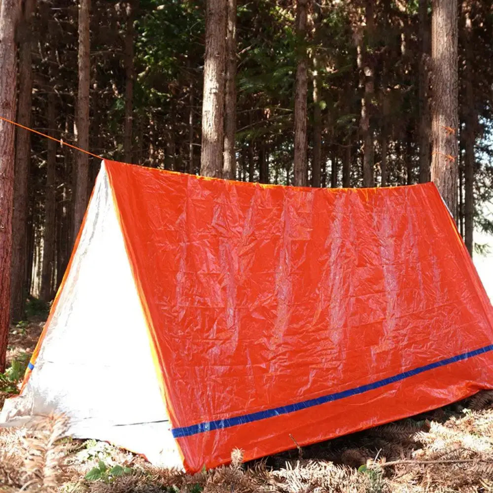 Outdoor Emergency Survival Tent and Blanket set up in a forest, showcasing the bright orange emergency camping shelter.
