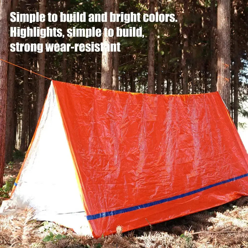 Outdoor Emergency Survival Tent and Blanket set up in a forest, showcasing bright colors and simple construction for emergency use.