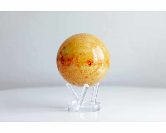 A rotating globe model representing the Sun, displayed on a stand, featuring a detailed yellow surface with red and orange hues.