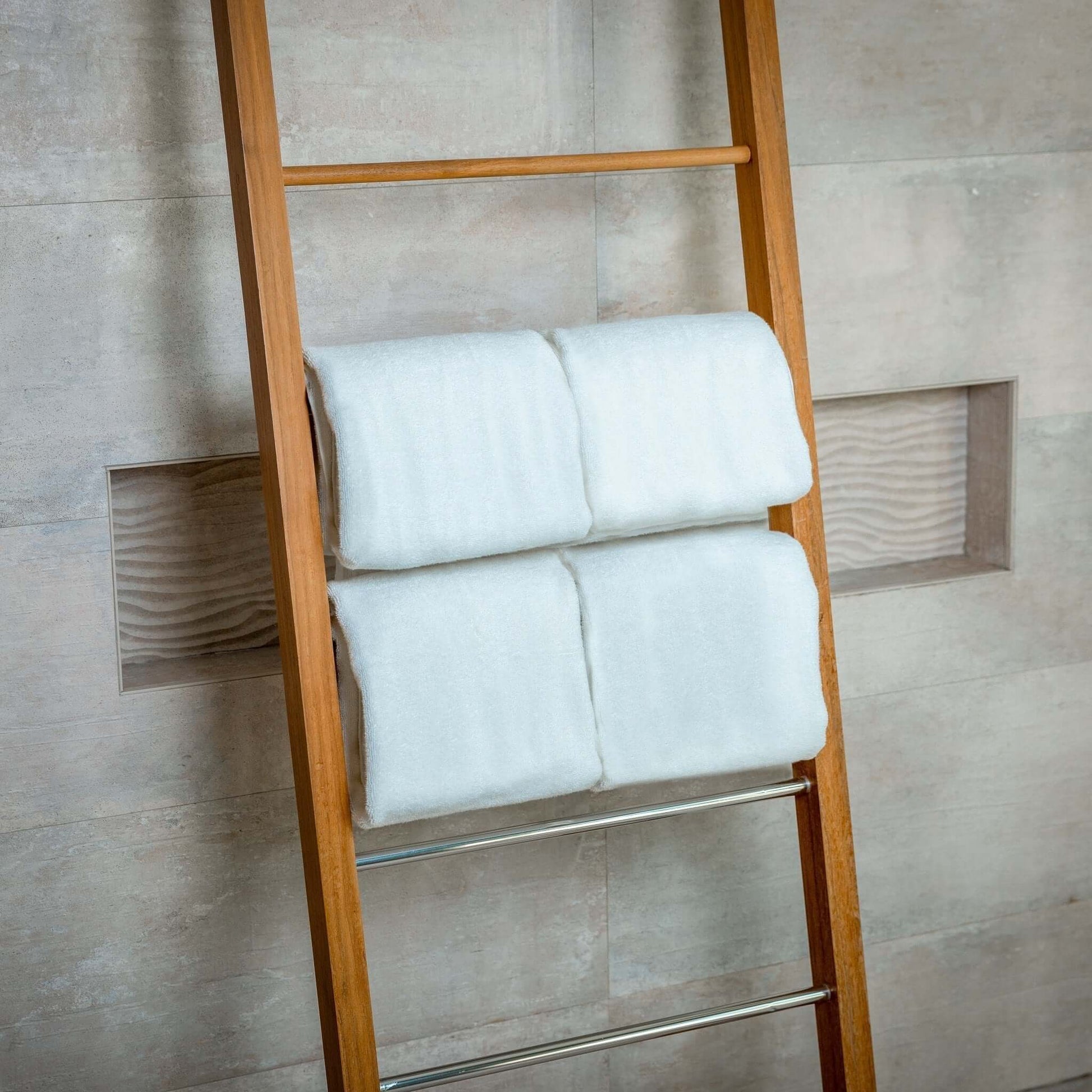 Luxury Organic Bath Towels displayed neatly on a wooden ladder against a modern tiled wall.
