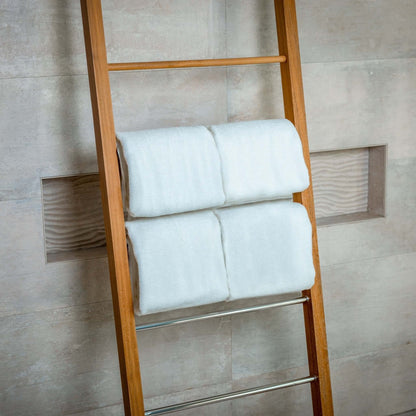 Luxury Organic Bath Towels displayed neatly on a wooden ladder against a modern tiled wall.