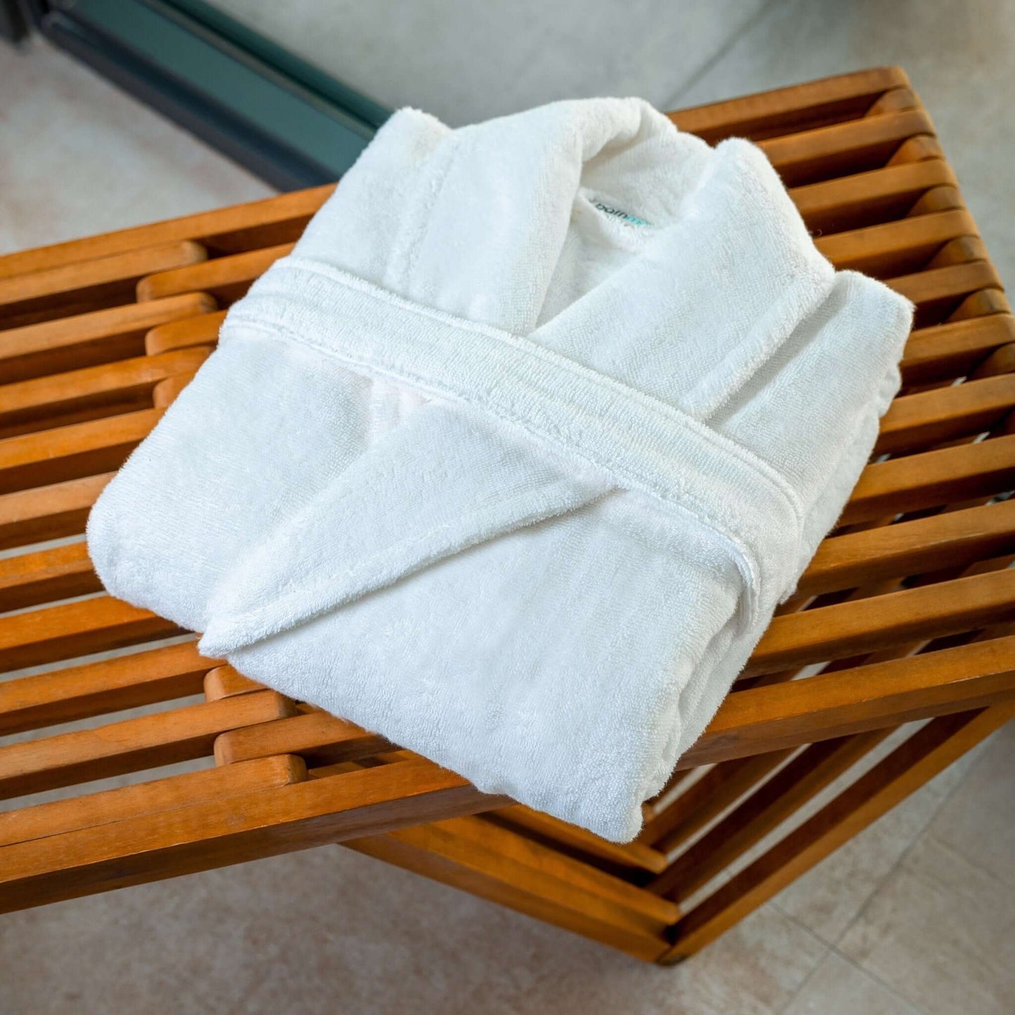 Luxury organic bathrobe folded on a wooden bench, showcasing its plush fabric and elegant design.