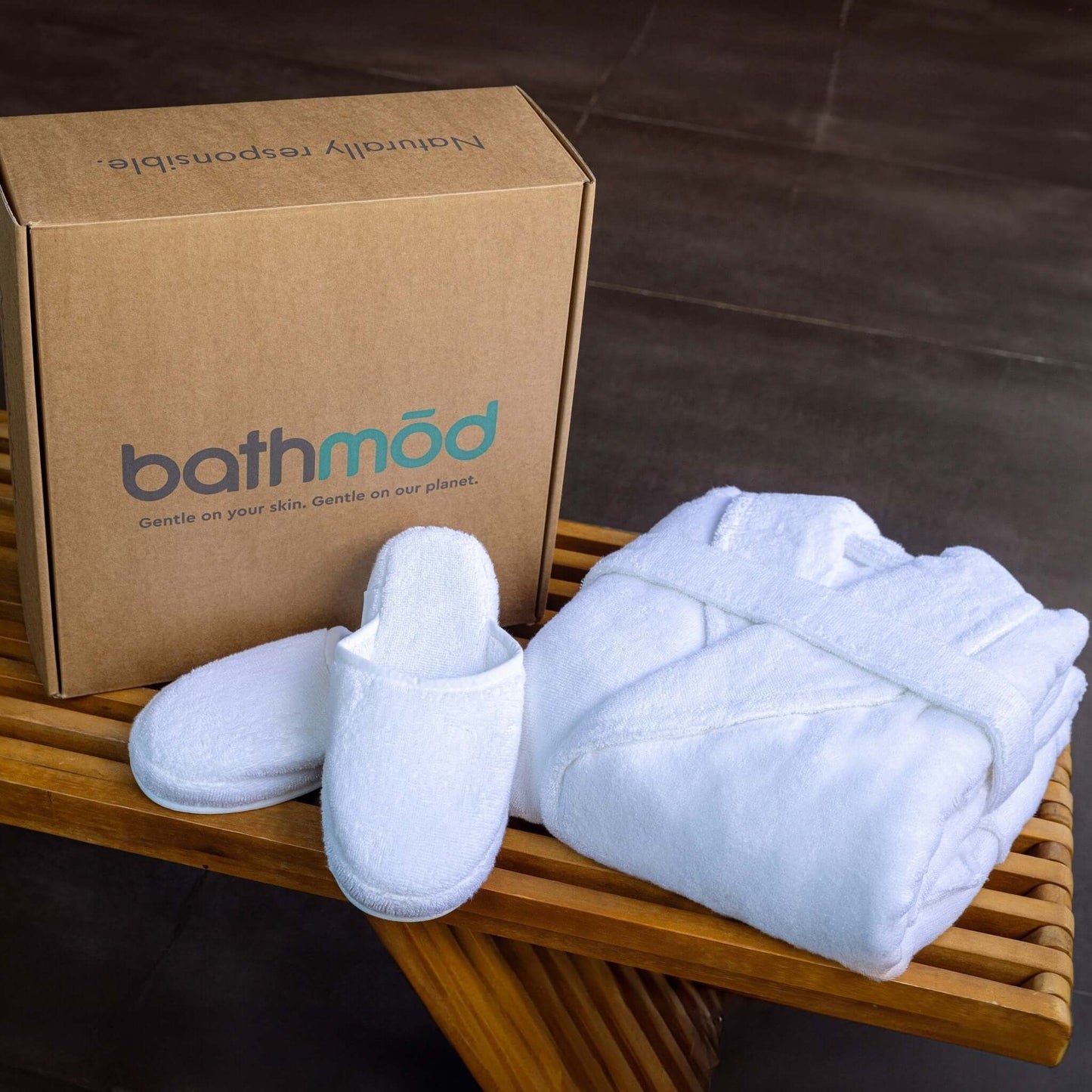Luxury organic bathrobe and slipper set displayed on a wooden table with a packaging box.