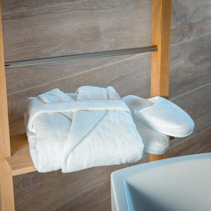 Luxury organic bathrobe and slippers set displayed on wooden rack in a modern bathroom.