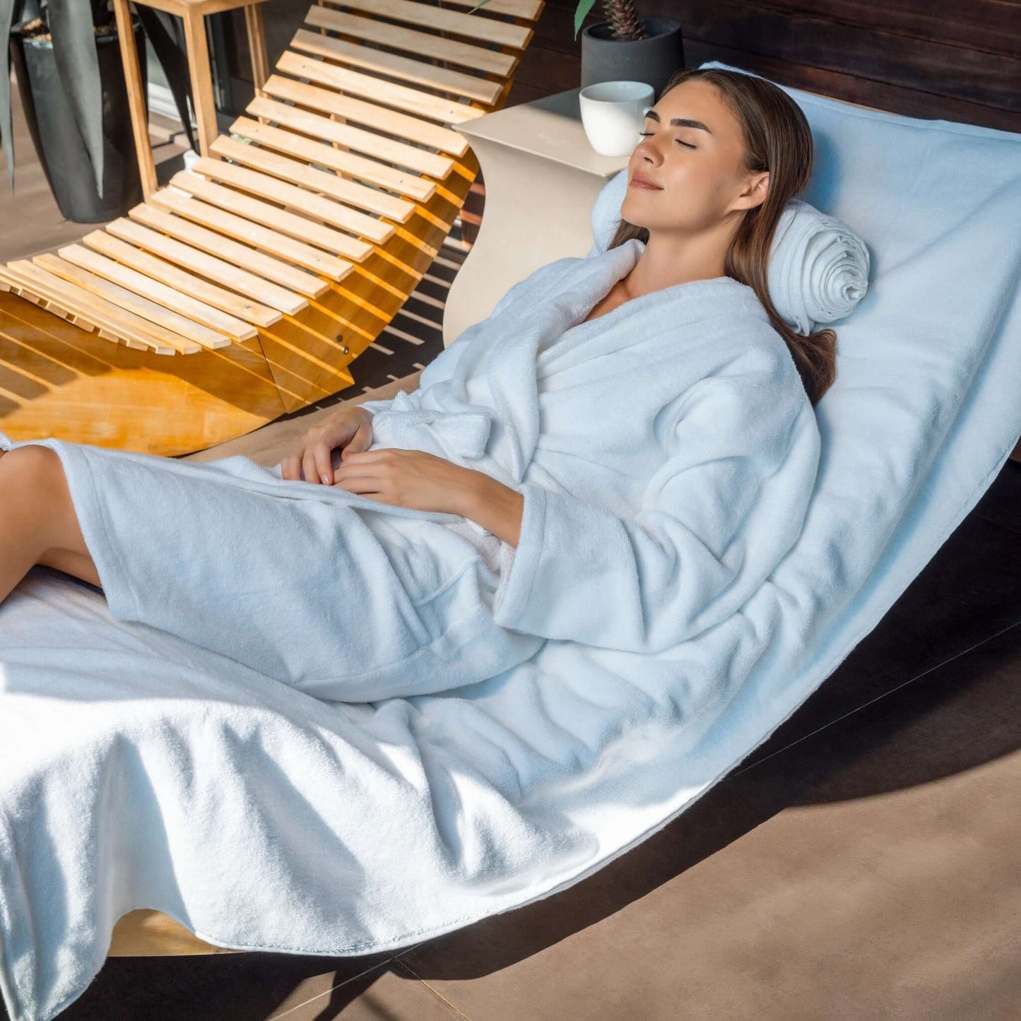 Luxury organic bathrobe worn by a woman relaxing on a lounge chair in a serene setting.