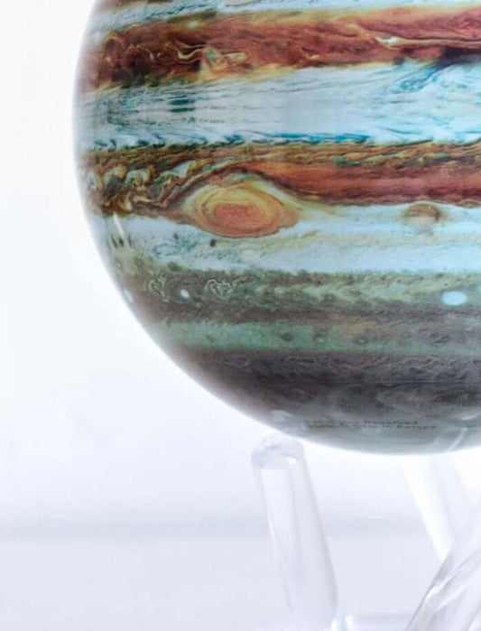 A self-rotating globe of Jupiter, featuring detailed bands of blue, brown, and orange, mounted on a clear acrylic stand.