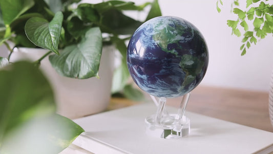 A realistic, rotating globe with a depiction of Earth from space, featuring blue oceans, green landmasses, and white cloud formations, supported by a clear stand.