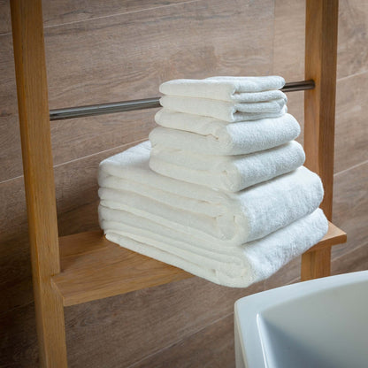 Luxury organic bath towel set stacked on a wooden shelf, showcasing soft, plush, eco-friendly towels.