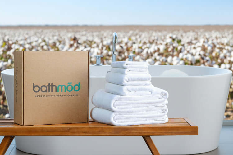 Luxury organic bath towel set of 6 pieces stacked next to a branded box on a wooden table.