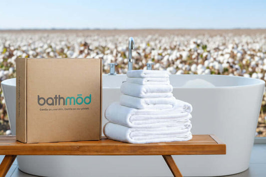 Luxury organic bath towel set of 6 pieces stacked next to a branded box on a wooden table.