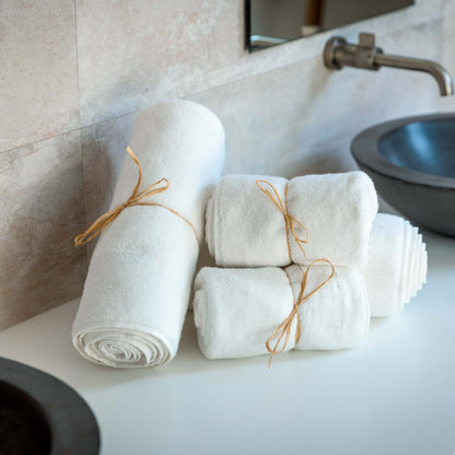 Luxury organic bath towel set displayed on a bathroom counter, featuring plush white towels tied with twine.