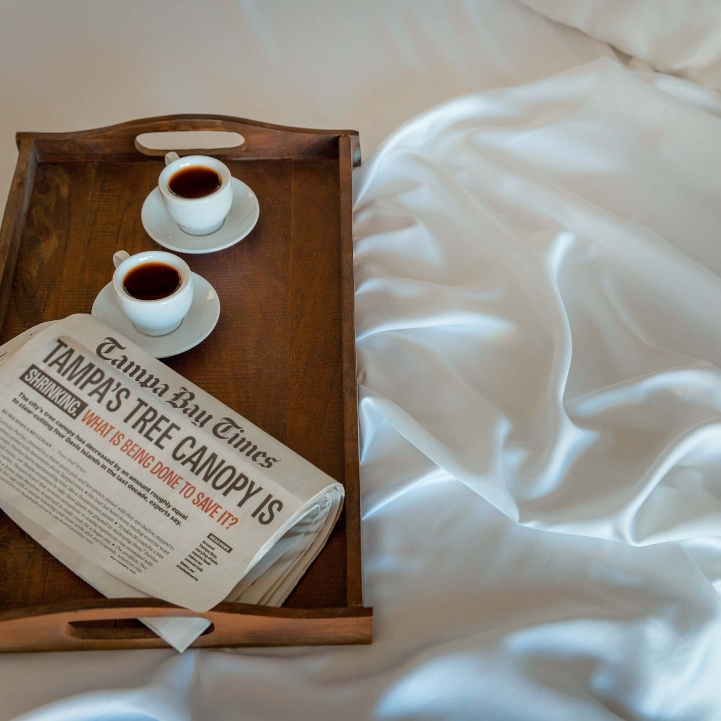 Eucalyptus silk sheets displayed with coffee cups and a newspaper on a tray, highlighting their luxurious softness.