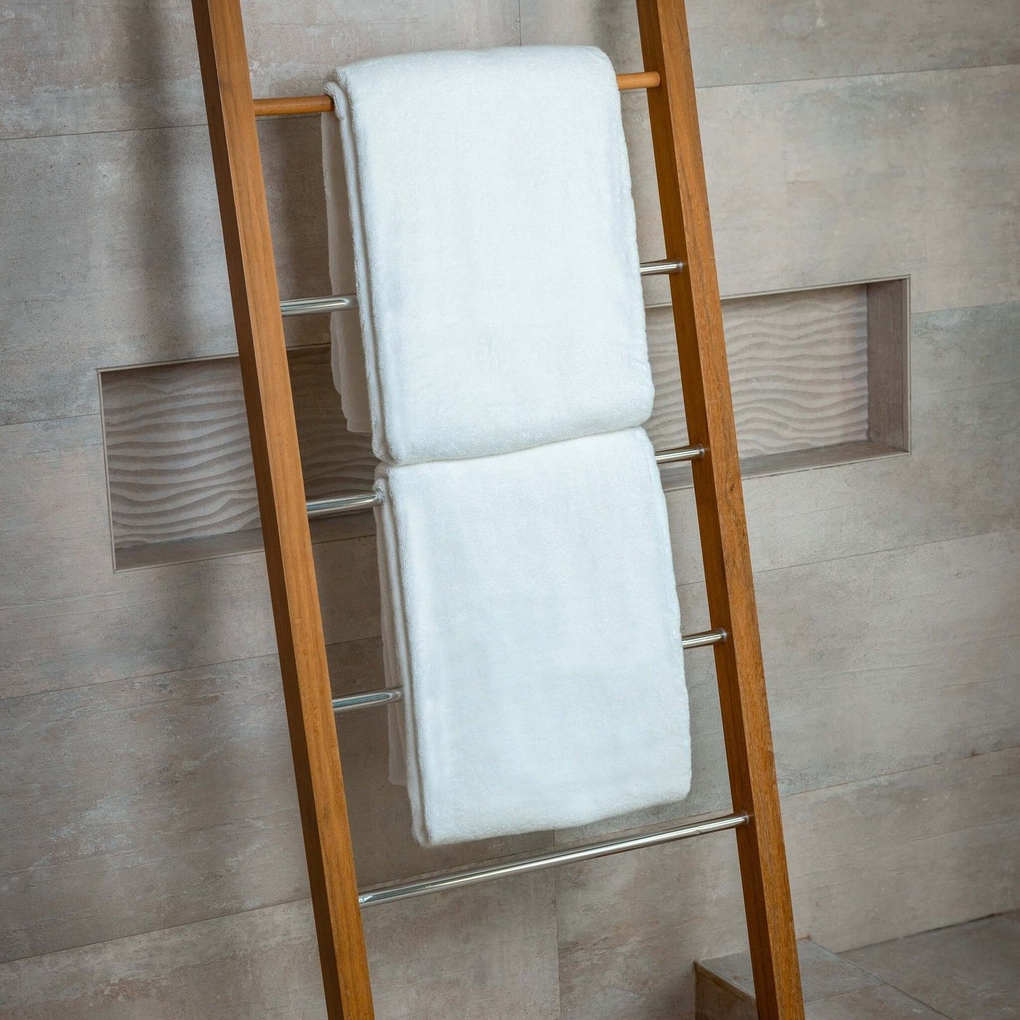 Luxury organic bath sheets displayed on a wooden ladder in a modern bathroom setting.